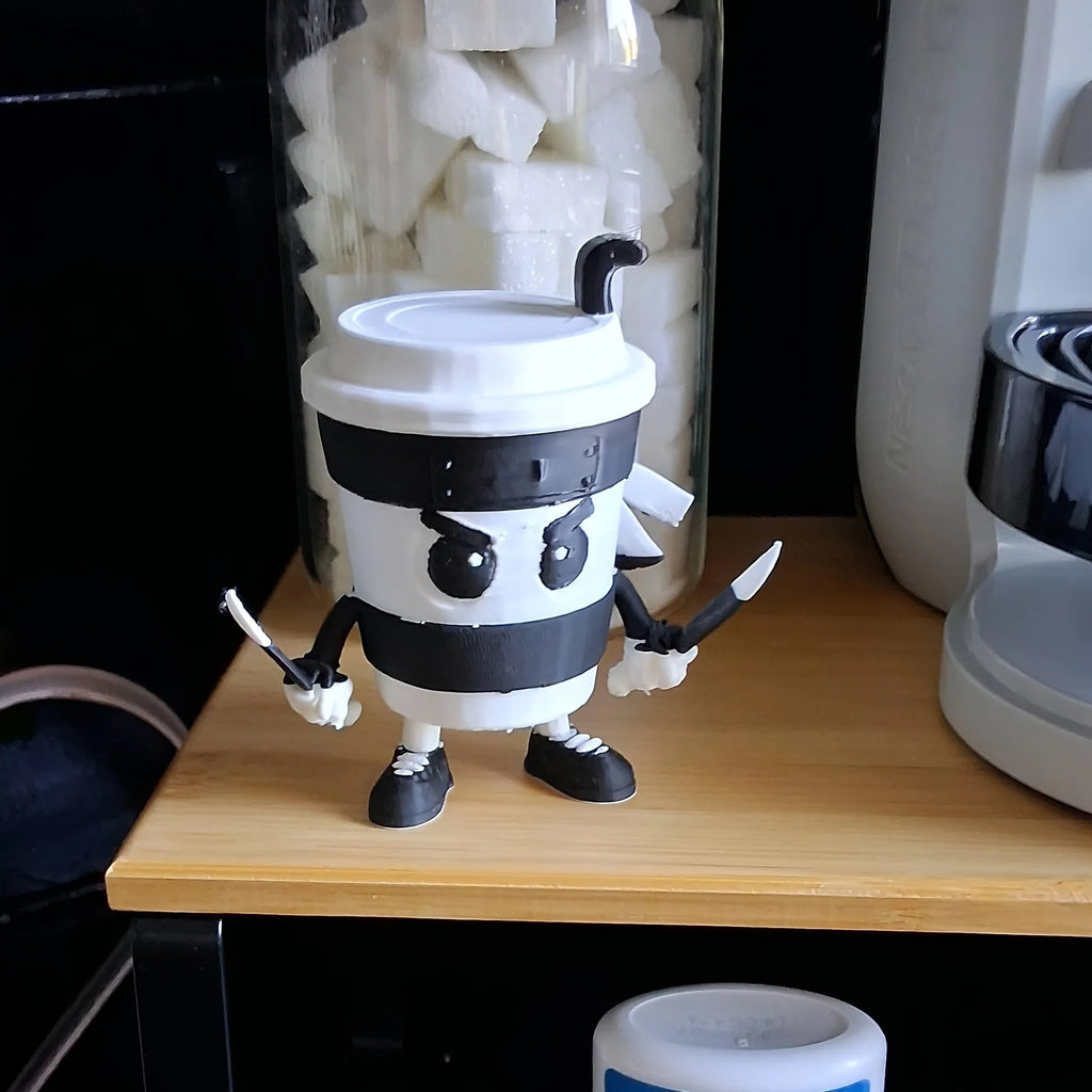 3D-printed Cappuccini Assassini Collector's Edition -  Animated character made from a coffee cup on a wooden surface with background kitchen items